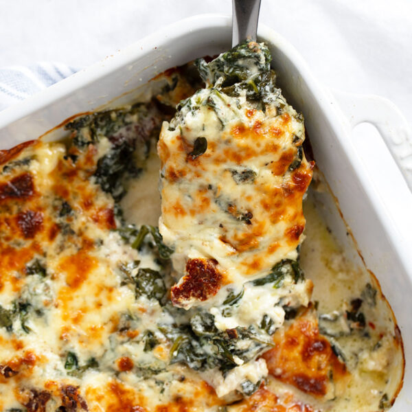 Baked Tuscan chicken in baking dish with spoon.