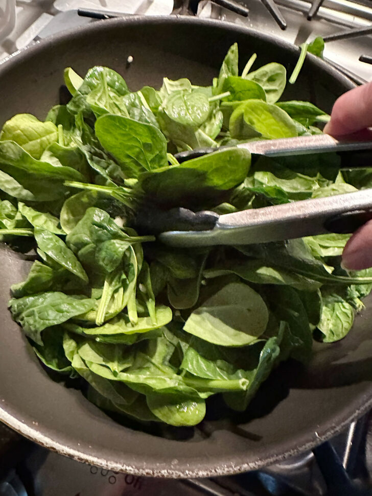 Wilting the spinach in a skillet.