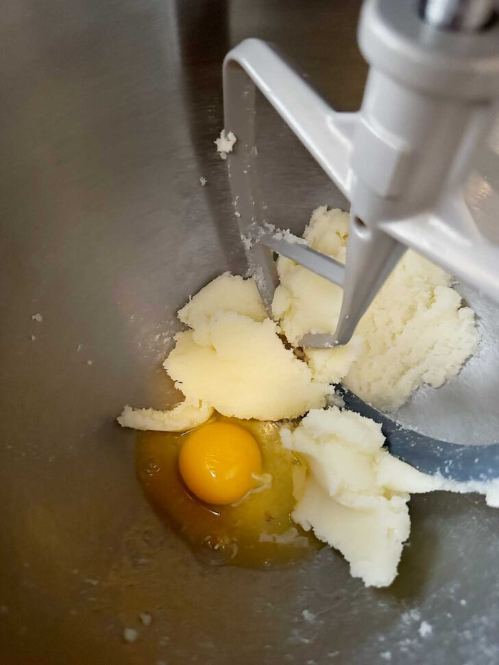Adding eggs to mixing bowl with the creamed butter and sugar.