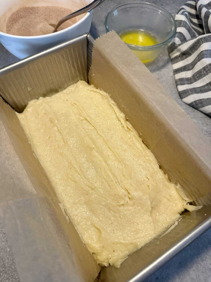 Adding half the batter to the loaf pan.
