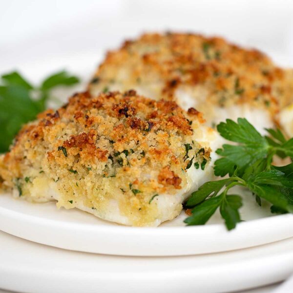 Panko crusted cod on plate with lemons and parsley.