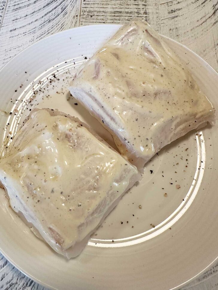 Mayo and mustard spread onto cod fillets.