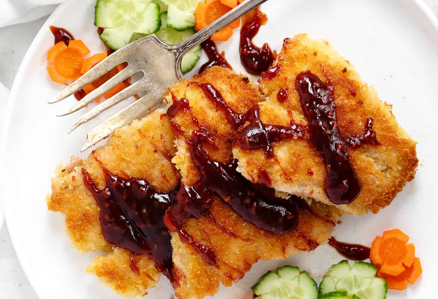 Salmon katsu with katsu sauce on a plate with vegetables.