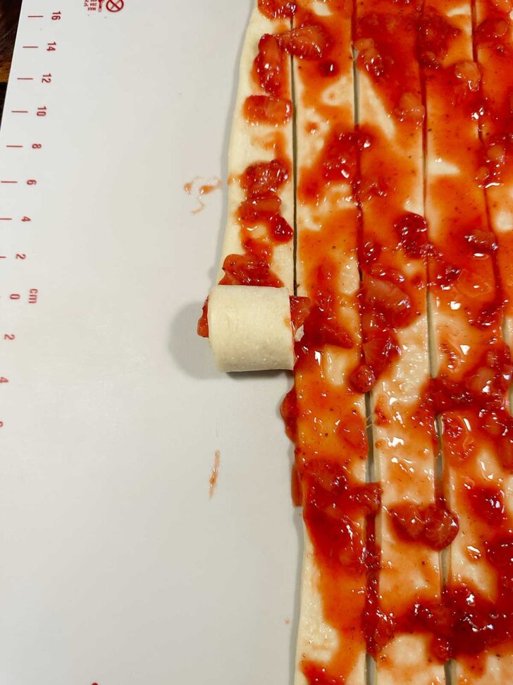 Rolling up the sliced dough and strawberries into rolls.
