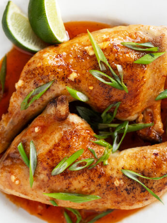 Hot honey chicken legs on plate with onion and lime.