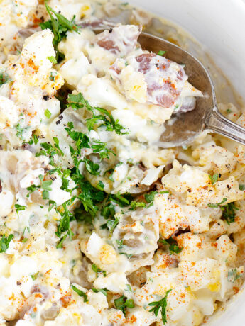 Devilled egg potato salad in bowl with spoon.