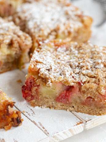Rhubarb custard cake sliced on serving board.