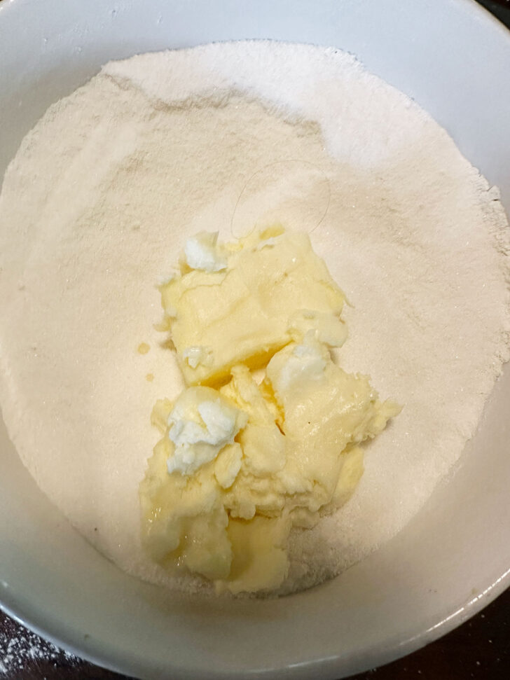 Adding softened butter to the dry ingredients for the filling.