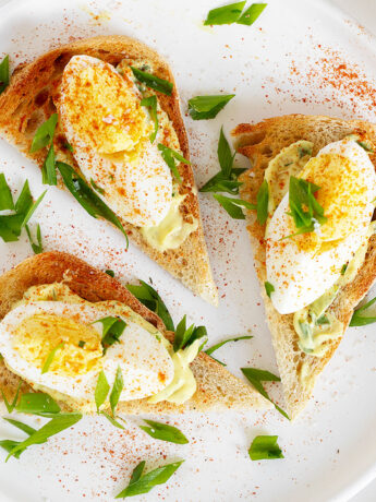 Open-faced devilled egg sandwiches on plate.