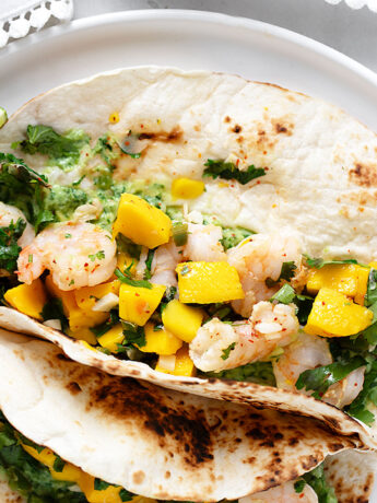 Shrimp tacos with mango on a serving plate.