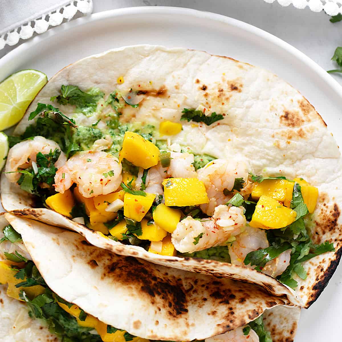 Shrimp tacos on a plate with mango.
