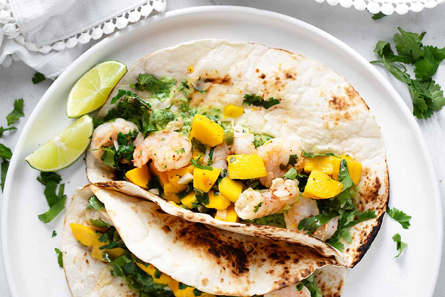 Mango shrimp tacos on serving plate.