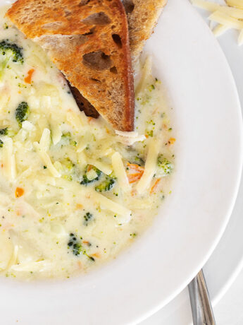 Creamy broccoli cauliflower cheese soup in a bowl with toast.