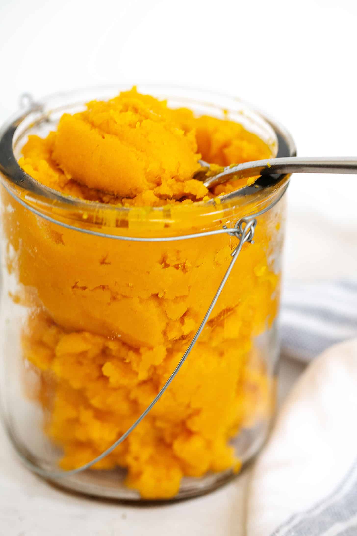 Homemade pumpkin puree in jar with spoon.