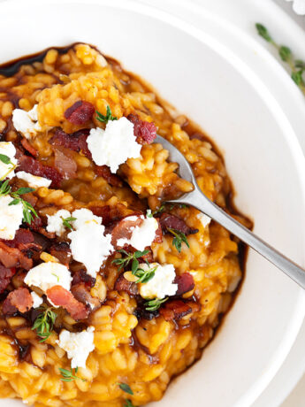 Pumpkin risotto in white bowl with fork.