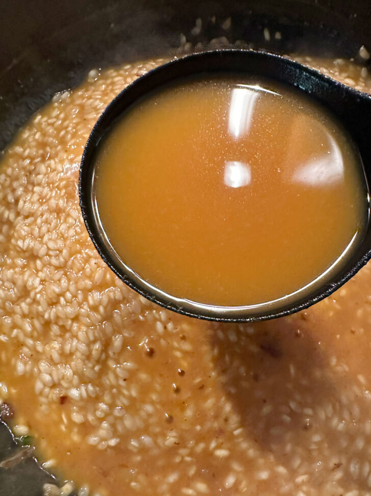 Adding a ladle of the broth and pumpkin mixture.