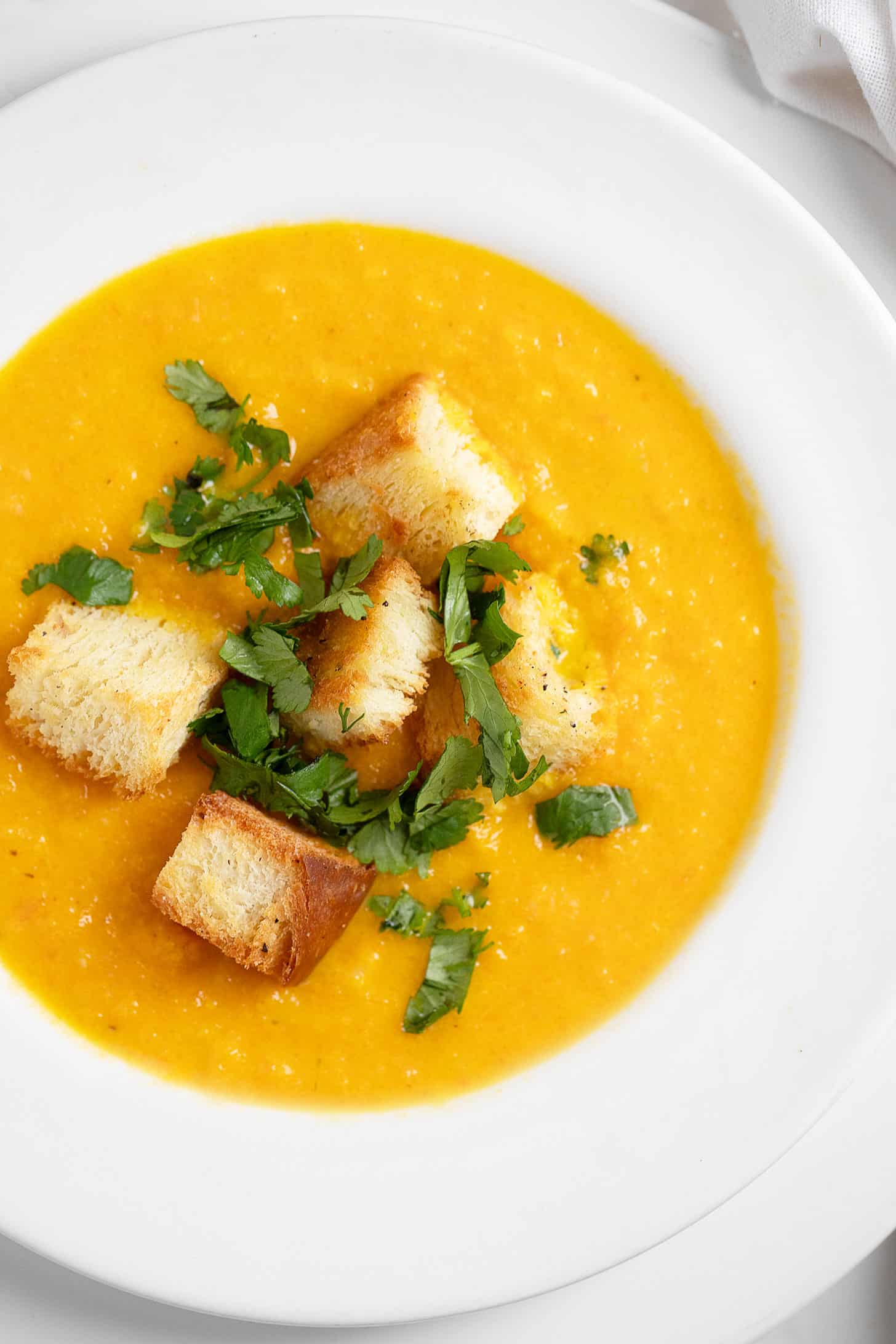 Carrot coriander soup in bowl with croutons.