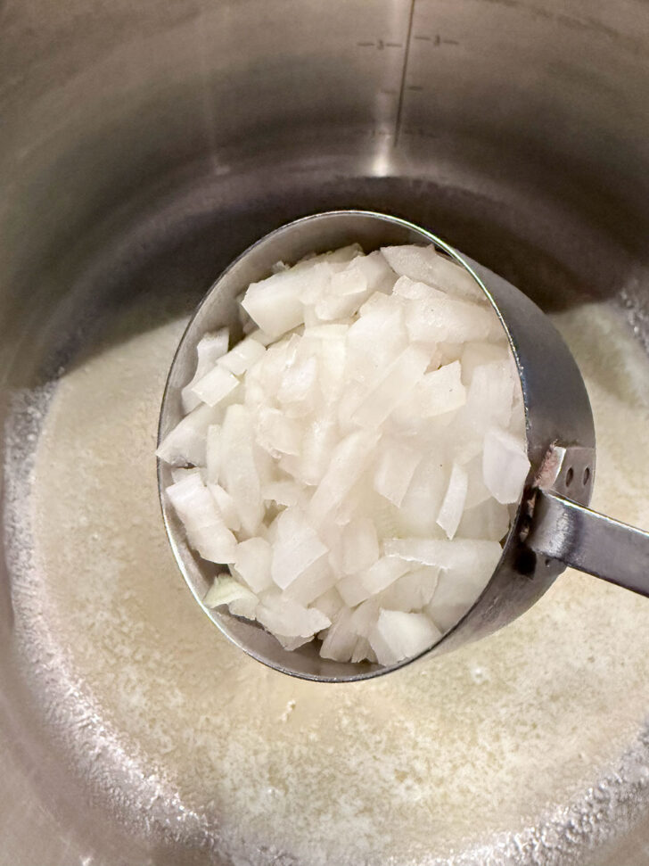Adding onion to melted butter in soup pot.
