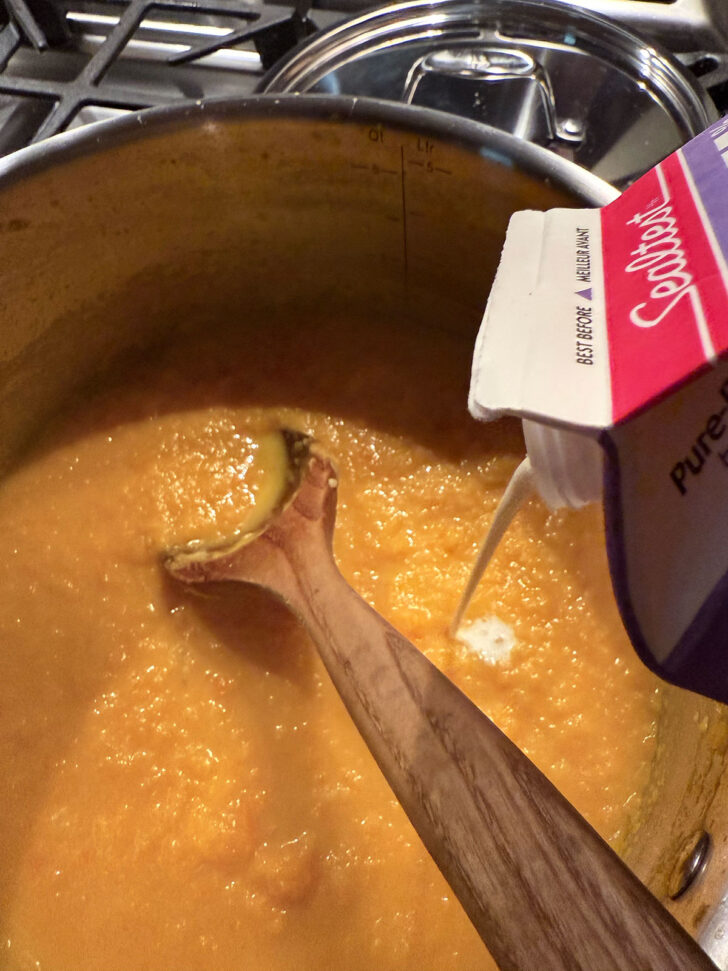 Adding a splash of cream to the soup.