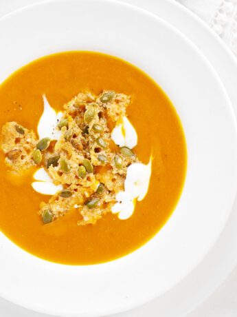 Kabocha squash soup in bowl with parmesan pepita topping.