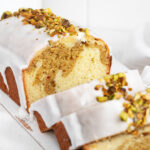 Lemon pistachio loaf sliced on serving board.