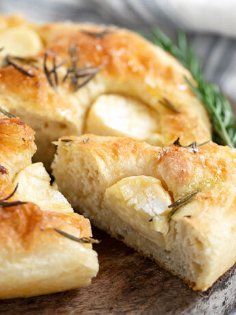 Mini Brie focaccia sliced on cutting board.