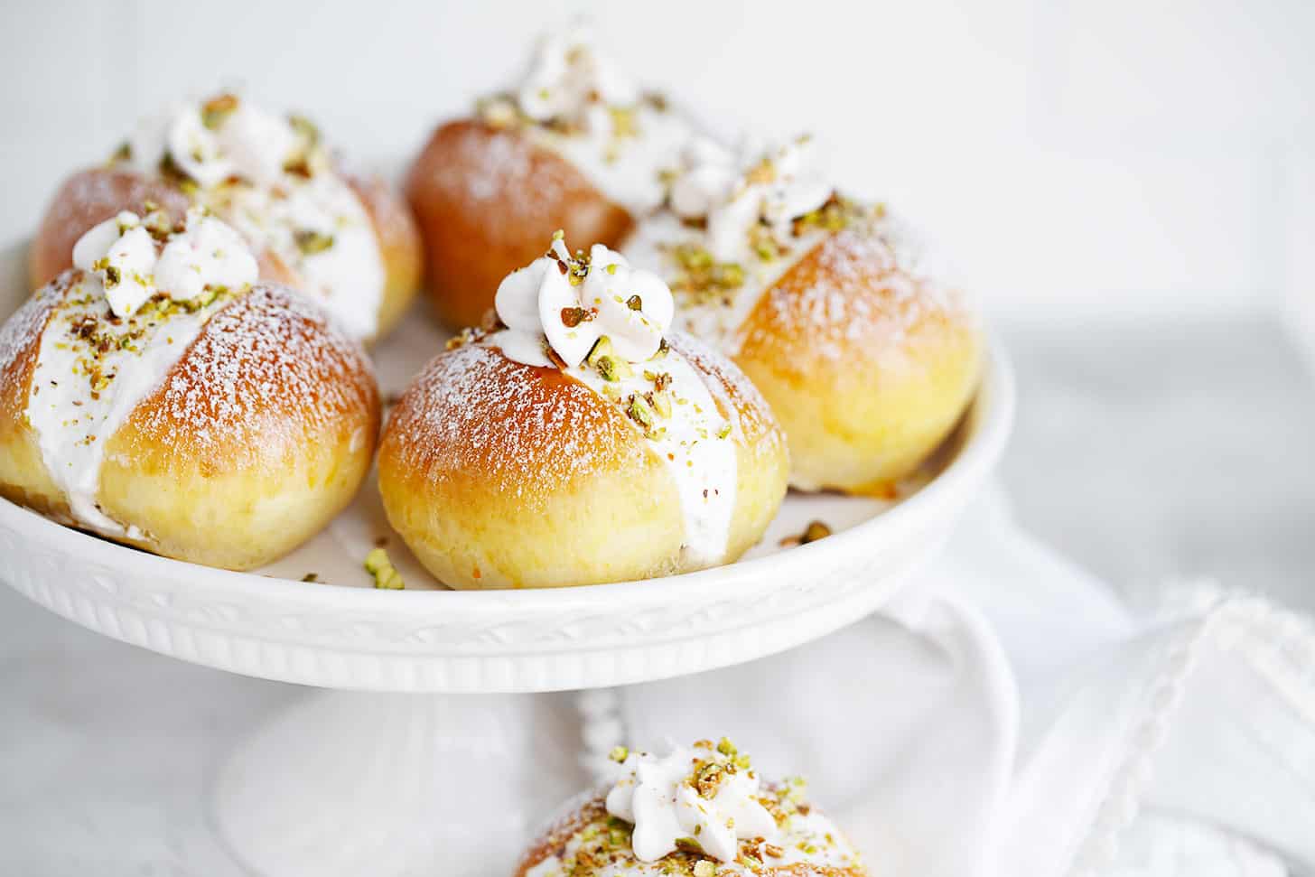 Pistachio maritozzi on a cake plate.