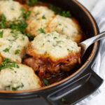 Red wine braised chicken with dumplings in cooking dish.