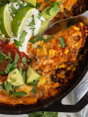 Chicken enchilada skillet in cast iron skillet with spoon.