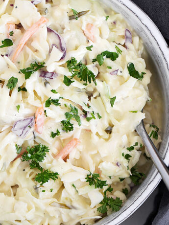 Dill pickle coleslaw in serving dish with spoon.