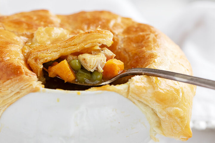 Curried chicken pot pie in baking dish with spoon.