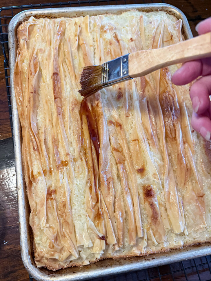 Baked phyllo being brushed with maple syrup.