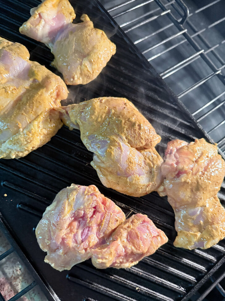 Marinated chicken on grill pan in oven.