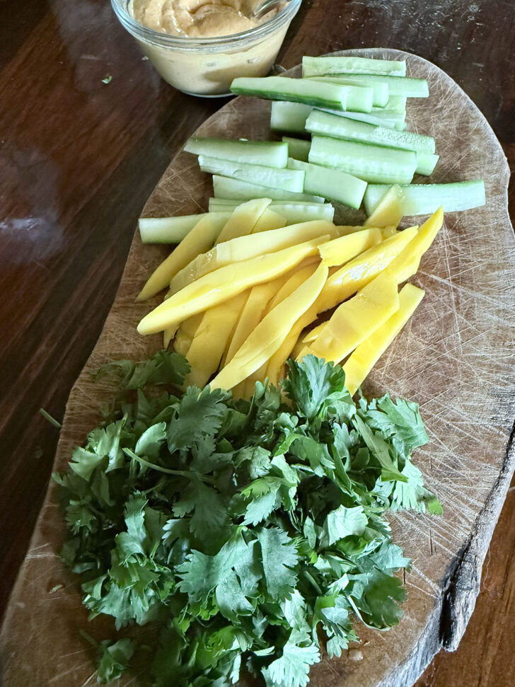 Vegetables and mango prepped on cutting board.