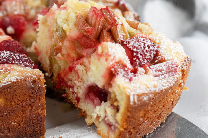 Strawberry rhubarb cake sliced on serving plate.