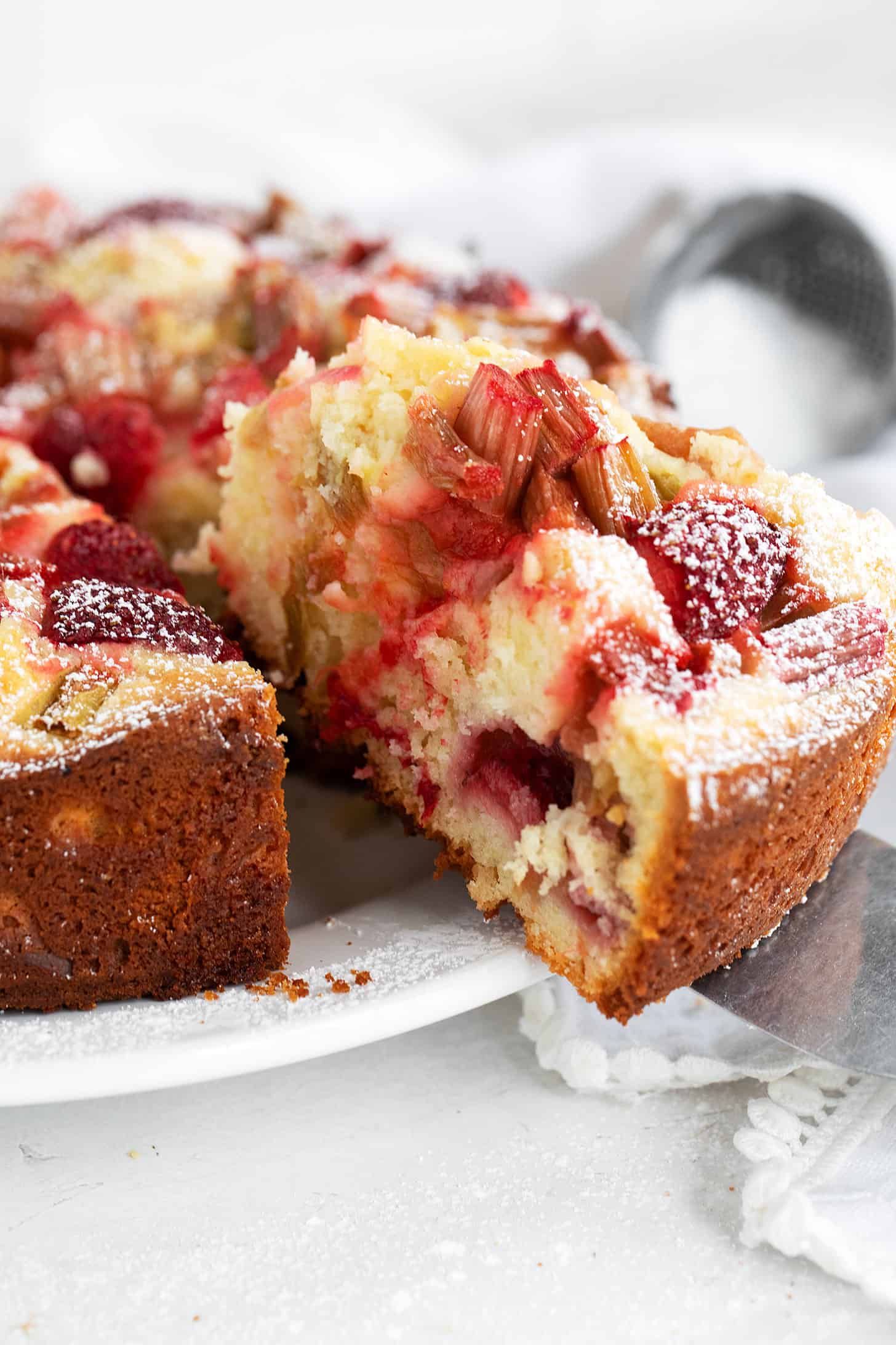 Strawberry rhubarb cake sliced on serving plate.