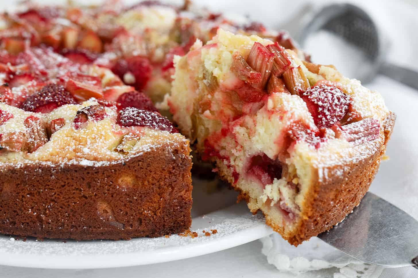 Strawberry rhubarb cake sliced on serving plate.