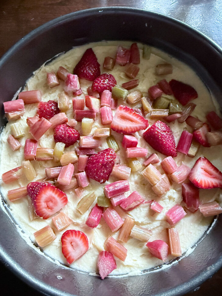 Half of the strawberries and rhubarb added to the top of the batter.