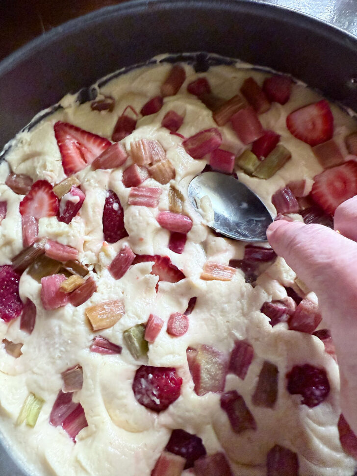 Using the back of a spoon to press the fruit into the batter.