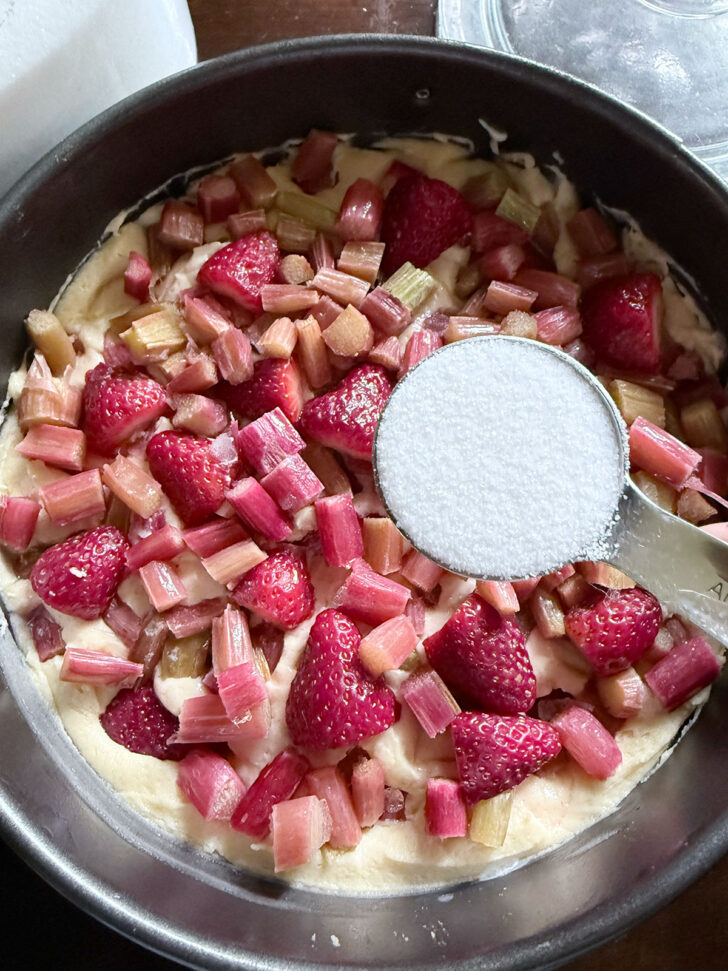 The remaining half of the rhubarb and strawberries added to the top of the cake and sprinkling with sugar.