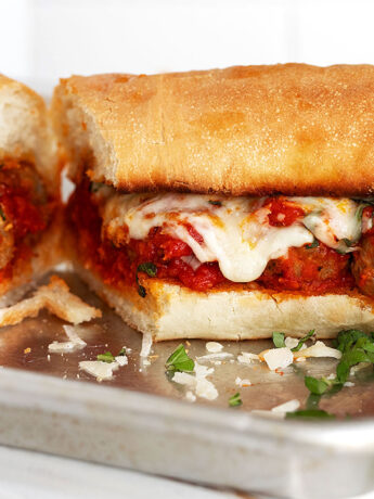 Meatball subs sliced in half on a baking sheet.