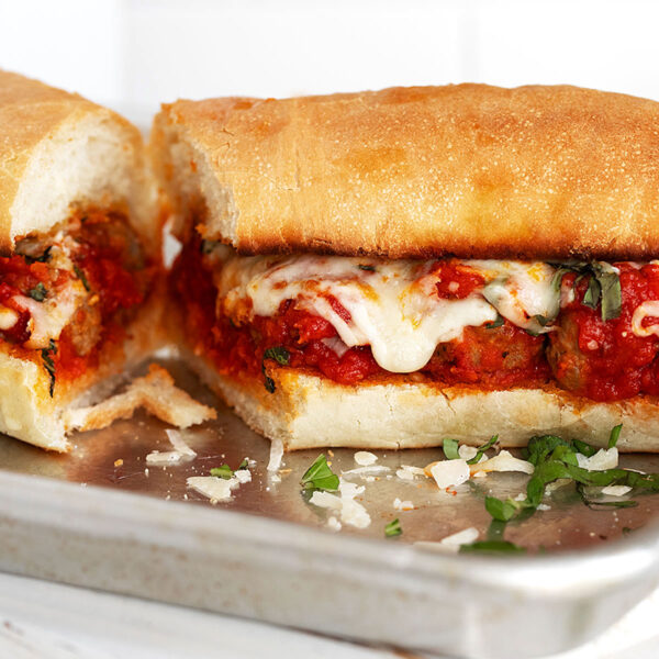 Meatball subs sliced in half on a baking sheet.