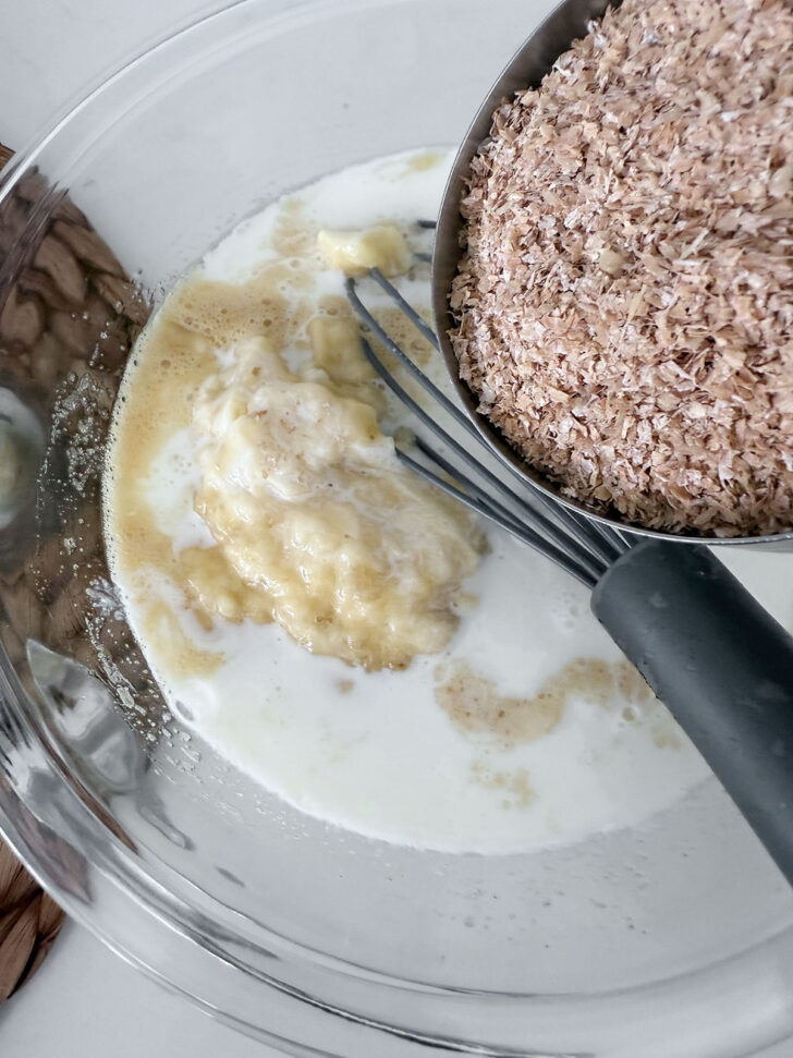 Adding wheat bran to wet muffin ingredients.