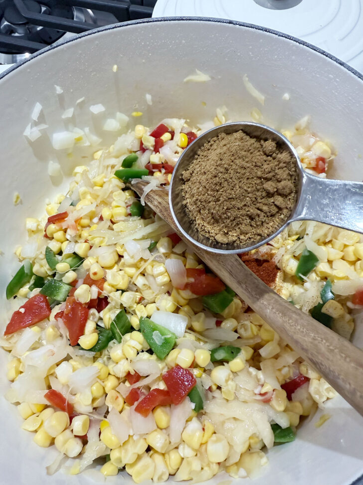 Adding cumin to the soup pot.