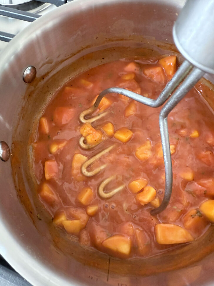 Breaking up the peaches with a potato masher.