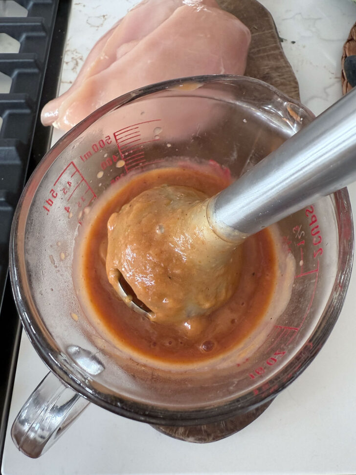 Smoothing the sauce with an immersion blender.