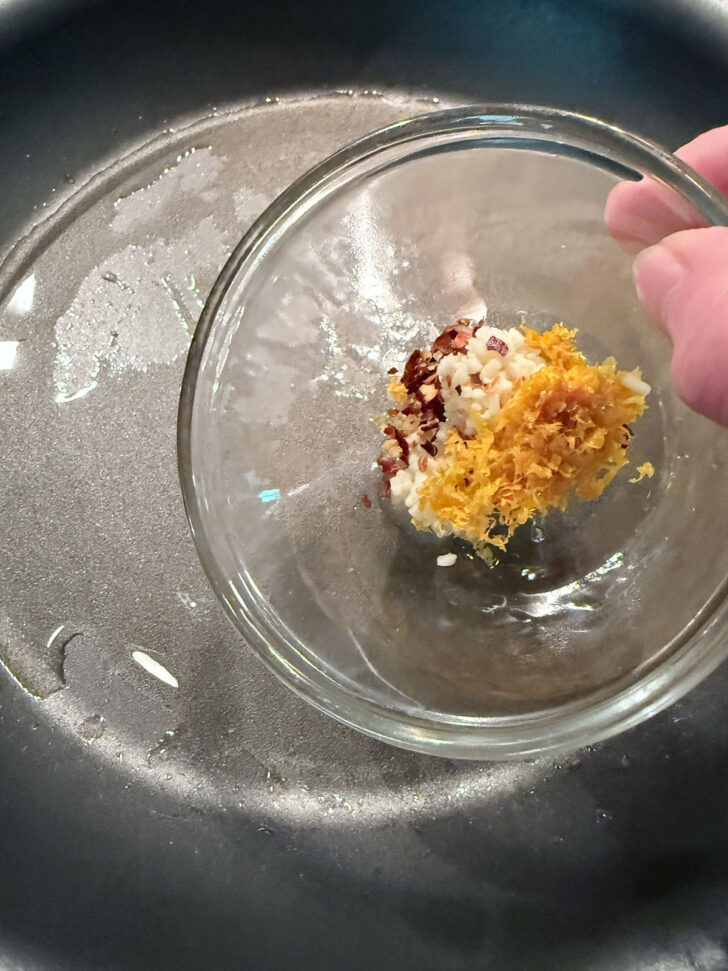 Adding orange zest and spices to a hot skillet.