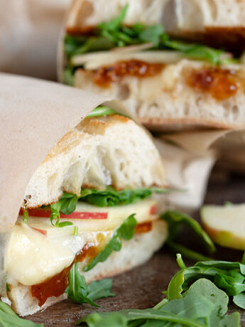 Apple, brie and fig jam sandwiches on a serving board.