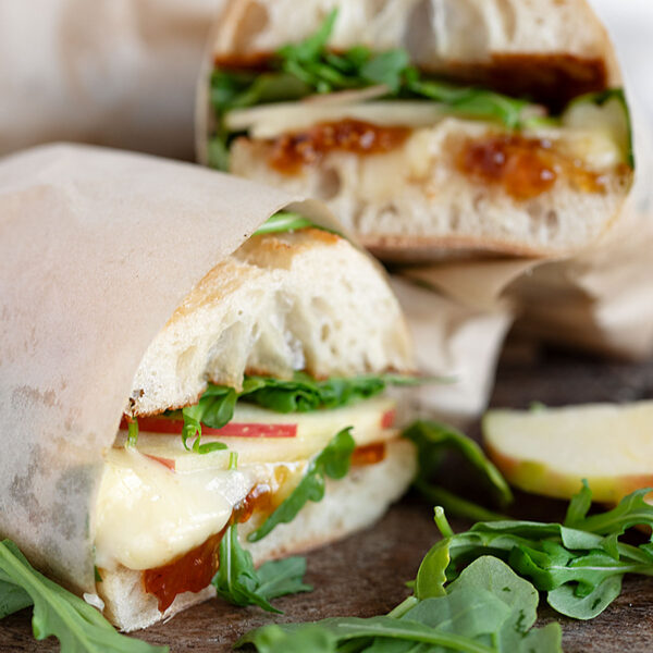 Apple, brie and fig jam sandwiches on a serving board.