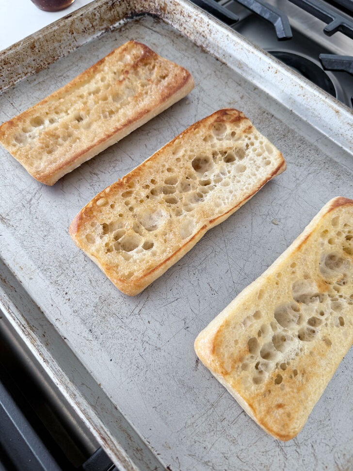 Ciabatta rolls on a baking sheet after toasting.